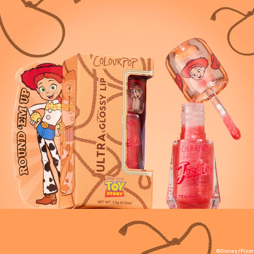ColourPop Ultra Glossy Lip Yeehaw gloss sparkles in a clear hexagonal bottle as the doe-foot wand lifts peachy-pink shimmer, displayed beside rope-print packaging featuring Toy Story’s Jessie on a warm peach backdrop; 0.12 oz.