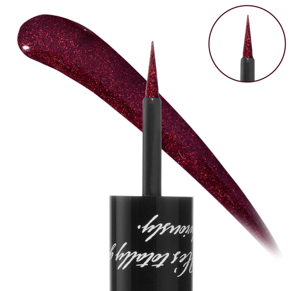 Vampire Graphix Ink Liner liquid brush draws a sparkling wine‑red swipe, with a fine tapered tip and black cap with script; an inset zoom highlights the applicator. ColourPop Graphix Ink Liner in deep burgundy shimmer for precise wings.
