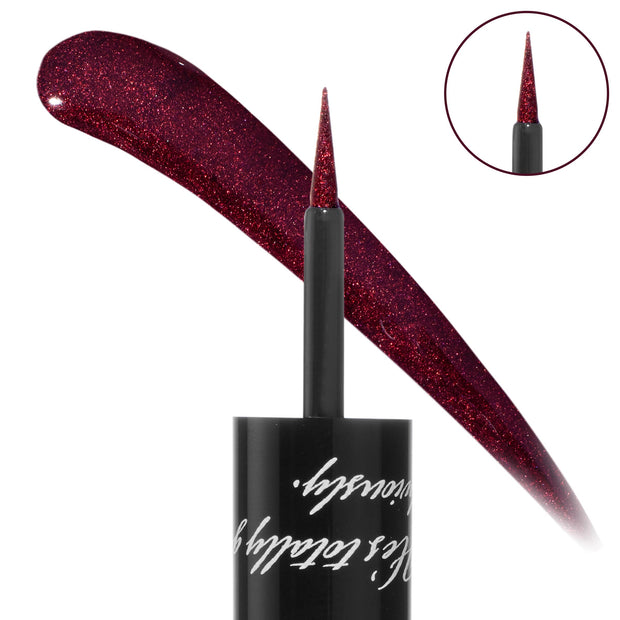 Vampire Graphix Ink Liner liquid brush draws a sparkling wine‑red swipe, with a fine tapered tip and black cap with script; an inset zoom highlights the applicator. ColourPop Graphix Ink Liner in deep burgundy shimmer for precise wings.