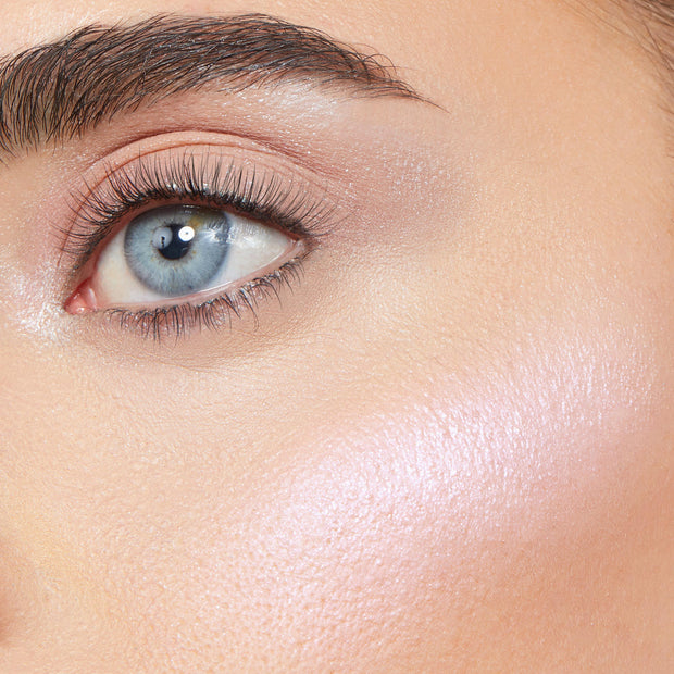 Vampire Skin ColourPop Super Shock Highlighter sweeping across the cheekbone, reflecting a pearlescent pink‑lilac glow next to a natural eye in a close-up face shot, showcasing dewy, high-shine payoff on skin.