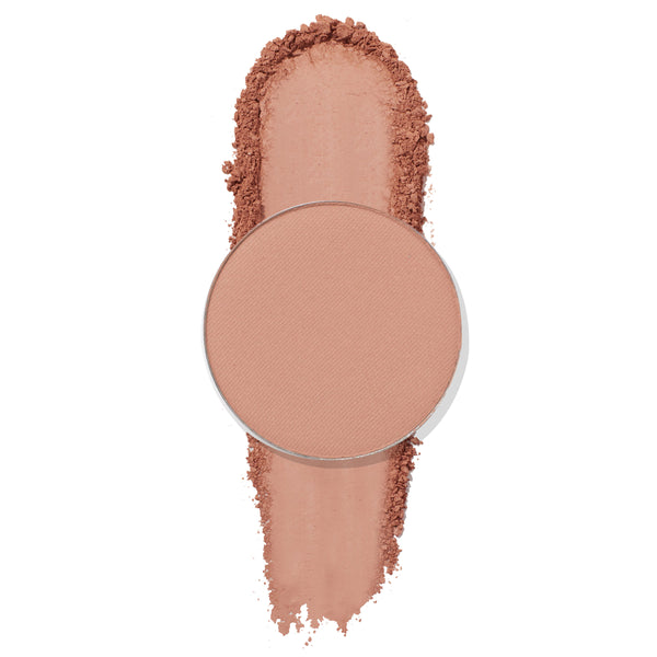 Single round pan of ColourPop Wake Up Call Pressed Powder Shadow showing a matte warm peachy-beige swatch, the pan centered over a vertical swipe of pigment on a white background.