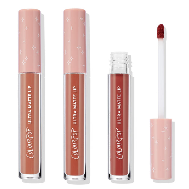 Warmed Up ColourPop Ultra Matte Lip set shows three full‑size tubes with peach star caps and one open doe‑foot applicator, revealing warm terracotta and deep reddish‑brown nude shades arranged on a clean white background.