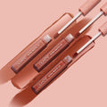 Three ColourPop Ultra Matte Lip tubes in Warmed Up, with doe-foot applicators swatching warm terracotta nude stripes on a peach backdrop, showcasing the ultra-matte liquid lipstick trio with star-print caps.