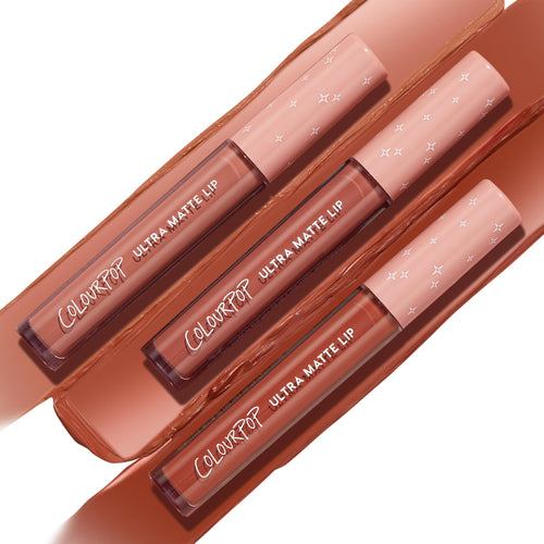 Three ColourPop Ultra Matte Lip tubes in Warmed Up lay diagonally across thick swatches, peach caps with white star prints, highlighting a warm terracotta nude liquid lipstick and long‑wearing matte finish.