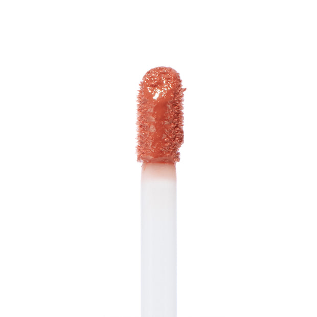 Doe-foot applicator coated in Zuma Ultra Blotted Lip by ColourPop, a warm peachy nude shade, captured in a crisp macro close-up against a clean white background.