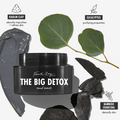 Black jar of Fourth Ray Beauty The Big Detox Mud Mask, a ColourPop Face Mask, centered with a glossy gray kaolin clay smear, eucalyptus leaves, and bamboo charcoal pieces, highlighting purifying, pore‑refining detox treatment for facial skin.
