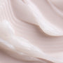 Coconut ColourPop Lip Mask swatched in thick, glossy white ribbons, showcasing a rich, cushiony texture and hydrating sheen on a smooth, pale pink surface.