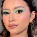Mint and teal gradient eye look created with the Just My Luck ColourPop Shadow Palette, shown in a close-up of a model with fluttery lashes, glossy nude lips, and a gold hoop earring under soft indoor light, showcasing bold green pigment.