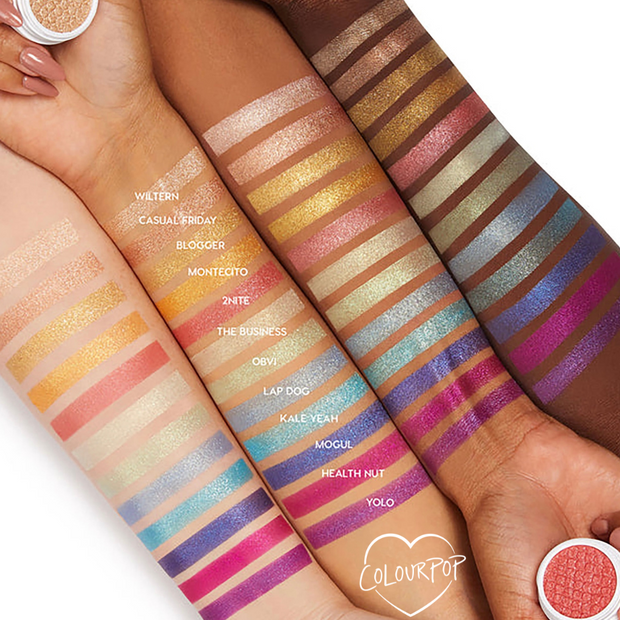 Obvi Super Shock Shadow by Colourpop swatched on multiple skin tones, showing its shimmery peachy-pink stripe among a rainbow of metallic Super Shock Shadow shades in an arm lineup, with small shadow pots framing the swatches.
