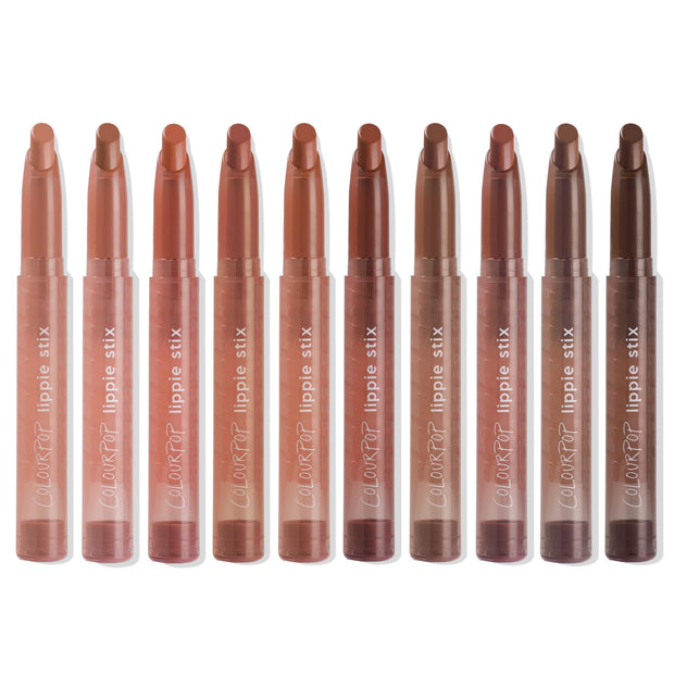 ColourPop Lippie Stix line up showing In the Nude collection - ten twist-up lipsticks in clear tubes, ranging from peach and pinky beige to warm caramel and deep brown - standing upright on a white background.