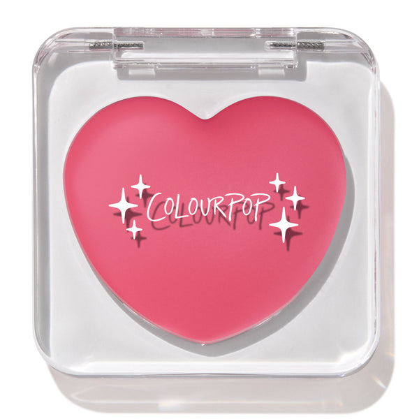 Heart-shaped bright rosy pink compact showcases the ColourPop Lip and Cheek Balm in Adore You, closed inside a clear square case with white logo and star accents, set against a clean white background.