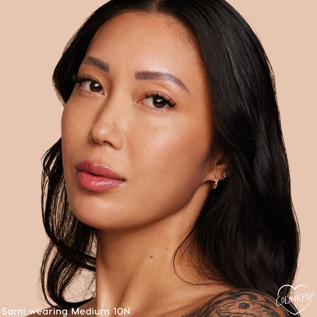 Model showing smooth, natural-looking complexion while wearing Colourpop Pretty Fresh Face Powder in shade Medium 10, highlighting even coverage and soft matte finish against a warm beige background.