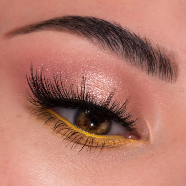 Shimmery peach‑pink eyeshadow with microglitter sweeps across the lid, paired with bold yellow waterline liner and full lashes, showcasing the Sweet As Can Bee ColourPop Shadow Palette on a close-up eye beneath a groomed brow.