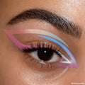Pastel graphic eyeliner sweeps across a model’s eyelid - pink, beige, mint, blue, lavender, and white - showcasing Sweet Fantasy, a ColourPop Shadow Palette & Brush Set, with crisp lines and soft shimmer in a clean close-up beauty shot.