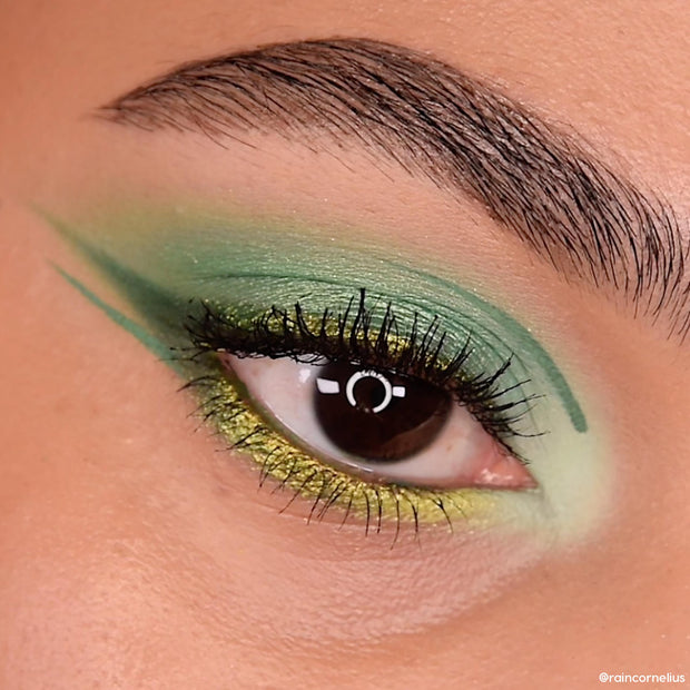 Green eye makeup blending lime shimmer to emerald with a sharp graphic wing and bright inner corner, shown in an extreme close-up of the eyelid and brow, created with the Just My Luck ColourPop Shadow Palette.