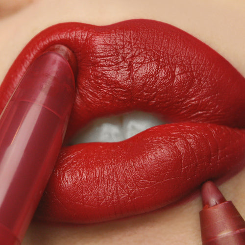 Bichette Lippie Stix by ColourPop coating full lips in a bold true red matte, the twist-up tip gliding along the lip line in an extreme close-up that highlights creamy texture, high pigment, and precise application.