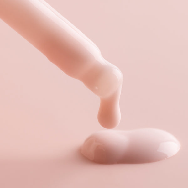 Dropper releasing creamy pink Watermelon Face Milk onto a soft blush surface, showcasing the silky, lightweight hydration and dewy glow of ColourPop Face Milk skincare.