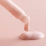 Dropper dispenses a creamy, pale-pink Rose Face Milk, forming a glossy droplet on a soft blush background, showcasing the ColourPop Face Milk serum in a minimal macro product shot.