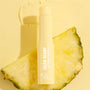 Selfie Ready Pore-Refining Serum Stick by Fourth Ray Beauty stands uncapped on a pineapple slice with a creamy swipe on a sunny yellow background, showcasing the Best Face Scenario face set from the ColourPop Face Set for smooth, selfie-ready skin.