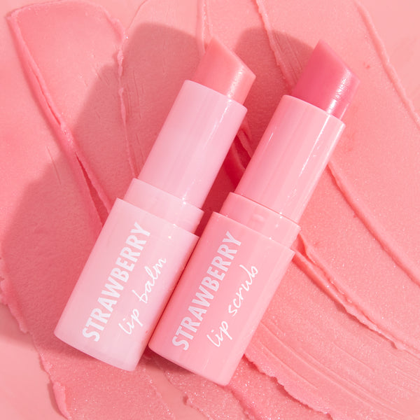 Strawberry lip balm and lip scrub sticks standing open on a swirled pink balm background, showcasing glossy, hydrating Colourpop-inspired Lip Gloss & Lip Oil finish in sleek light-pink tubes for soft, nourished lips.