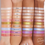 Roy G. Biv Super Shock Shadow by ColourPop swatched - sparkling rosy pink with fine shimmer - striped on three forearms of different skin tones, displayed among labeled shades under studio lighting to show color payoff and shift.