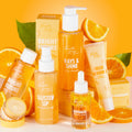 RAYdiate Vitamin C Serum dropper bottle stands front-center, showcasing golden liquid as the featured ColourPop Face Serum, surrounded by Fourth Ray citrus skincare, orange slices, and boxes on a bright orange backdrop.