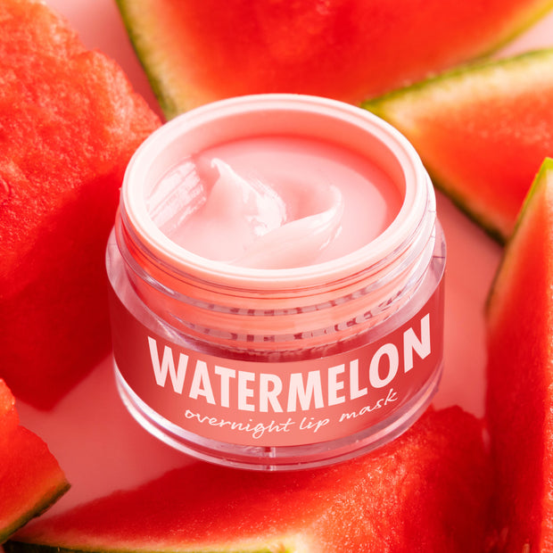 ColourPop Watermelon Lip Mask jar sits open with a glossy pink cream swirl, labeled “WATERMELON,” surrounded by ripe watermelon wedges on a light surface, highlighting the hydrating overnight lip treatment.