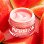 ColourPop Watermelon Lip Mask jar sits open with a glossy pink cream swirl, labeled “WATERMELON,” surrounded by ripe watermelon wedges on a light surface, highlighting the hydrating overnight lip treatment.