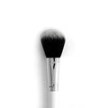 Blush brush with tapered, fluffy black-to-white synthetic bristles blending powder across cheeks, anchored by a chrome ferrule and white handle on a clean white background; ColourPop Makeup Brush for precise, soft application.