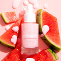 Pink dropper bottle of Fourth Ray Beauty Watermelon Face Milk standing amid fresh watermelon slices, creamy pink formula dripped on a blush background; a hydrating 0.95 fl oz ColourPop Face Milk with a juicy, summery skincare vibe.