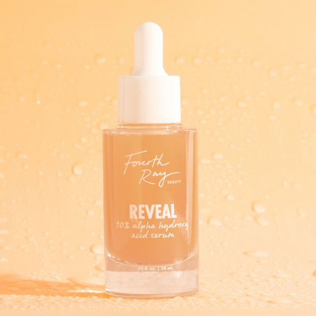 Glass dropper bottle of Fourth Ray Beauty Reveal 10% AHA Serum standing upright with a white cap and peach-tinted liquid against a dewy peach background, a ColourPop Face Serum exfoliant for smoother, glowing skin, 0.95 fl oz (28 ml).