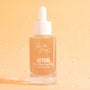 Glass dropper bottle of Fourth Ray Beauty Reveal 10% AHA Serum standing upright with a white cap and peach-tinted liquid against a dewy peach background, a ColourPop Face Serum exfoliant for smoother, glowing skin, 0.95 fl oz (28 ml).