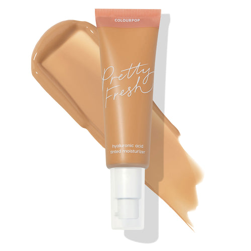Pump-top tube of ColourPop Pretty Fresh Tinted Moisturizer, shade Medium 12 W (warm medium, with hyaluronic acid), lying across a creamy tan swatch on a white background, highlighting a hydrated, sheer-coverage finish.