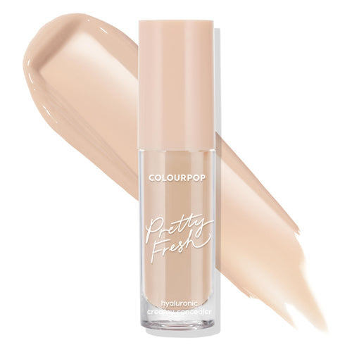ColourPop Pretty Fresh Creamy Concealer Light 50 W bottle stands upright, blush cap and clear tube reading hyaluronic, with creamy light‑beige swatches behind showing shade and coverage against a clean white background.