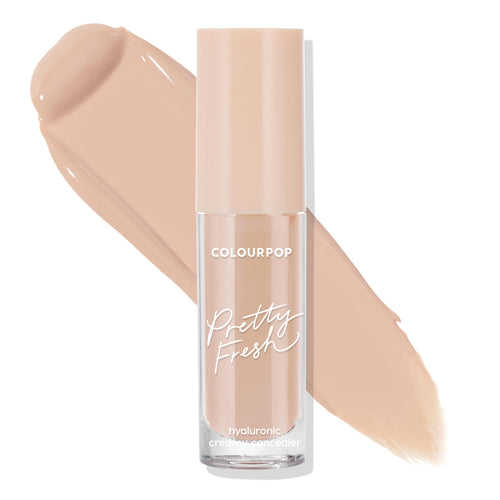 ColourPop Pretty Fresh Creamy Concealer, Light 60 N, stands upright in a clear tube with peach cap and white script, hyaluronic formula, shown with broad light neutral beige swatches behind on a white background.