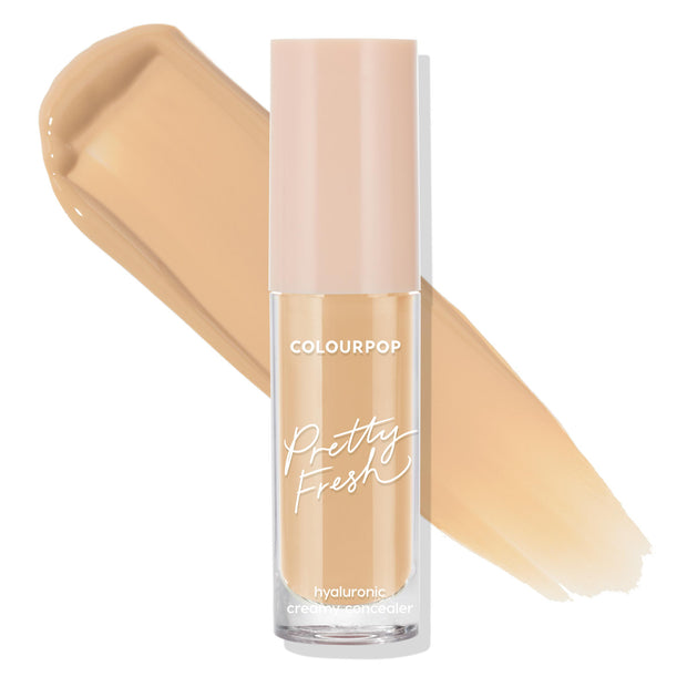 ColourPop Pretty Fresh Creamy Concealer in Medium 90 W stands upright, revealing its hydrating hyaluronic formula; clear tube with blush-pink cap set against two wide warm medium beige swatches on a white background.