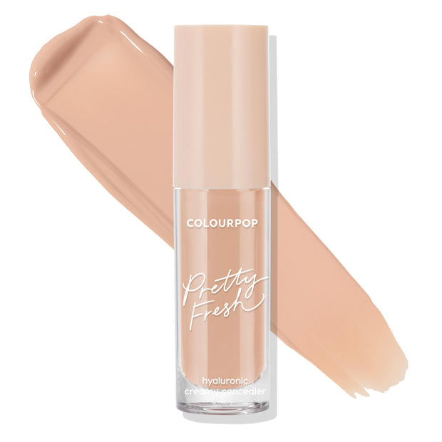 ColourPop Pretty Fresh Creamy Concealer in Medium 105 N stands upright, its frosted clear tube with blush cap and white script logo set before a smooth warm neutral beige swatch, highlighting the hyaluronic creamy formula on a white background.
