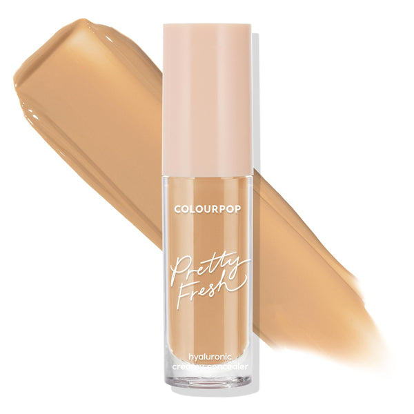 ColourPop Pretty Fresh Creamy Concealer in Medium Dark 120 W stands upright with a blush-pink cap, while a matching warm medium-dark swatch streaks behind the clear tube, highlighting the hyaluronic creamy formula on a white background.