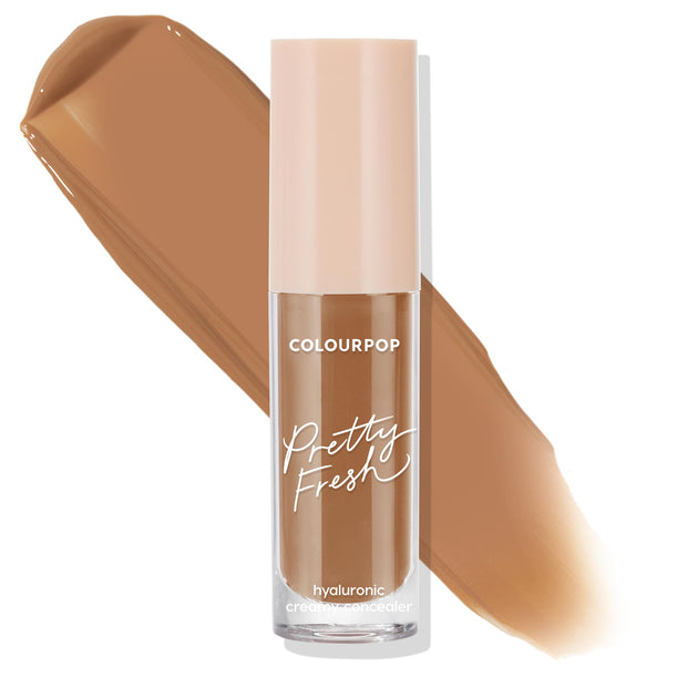 ColourPop Pretty Fresh Creamy Concealer in Dark 175 N stands upright, displaying a clear tube with blush cap and hyaluronic formula as a rich neutral-brown swatch sweeps behind on a white background, showcasing the shade and coverage.