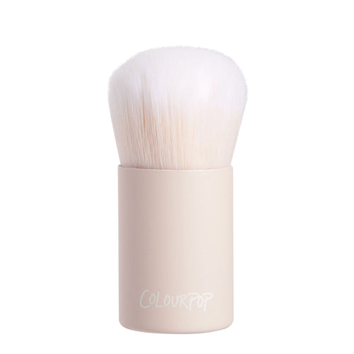Mini Kabuki Face Brush with dense white bristles and a matte beige short handle branded ColourPop stands upright, ready to buff and blend foundation or powder; compact ColourPop Makeup Brush on a clean white background.