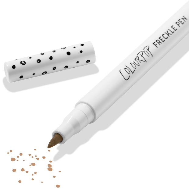 ColourPop Freckle Pen in Soft Brown uncapped, felt-tip applying scattered soft brown freckle dots, with polka-dot white cap beside it on a clean white background; long-wearing, buildable faux freckles makeup.
