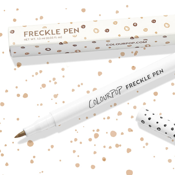 Soft Brown ColourPop Freckle Pen uncapped, felt-tip applicator ready to dot natural-looking freckles, shown with polka-dot cap and matching box on a white background speckled with brown spots; 1.0 ml makeup pen for faux freckles.