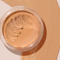 ColourPop SOL Face & Body Bronzing Balm in Fair showing a creamy, light tan bronzer with a scooped swirl in a clear round jar, set on a broad matching swatch that highlights its smooth, blendable texture for face and body.