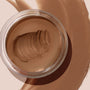 Open jar of ColourPop SOL Face & Body Bronzing Balm, shade Deep, revealing a creamy warm bronze formula with a swirled scoop, set against a broad matching swatch to showcase texture and payoff.