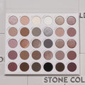 Stone Cold Fox ColourPop Shadow Palette lies open, displaying 30 cool-toned neutrals - taupes, mauves, grays, and browns - in matte, shimmer, and metallic finishes inside a white case on a light textured surface with the logo partly visible.
