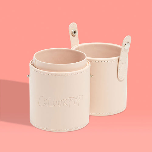 Small Stash Cup by ColourPop standing open - two beige faux‑leather cylindrical holders with snap tabs and stitching - for storing makeup brushes, tools, and accessories, displayed on a peach background.