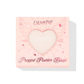 ColourPop Kiss 'N Tell pressed powder blush compact displays through a heart-shaped window in a pink box with winged-heart graphics, front-facing on a white background, 4.45g (0.16 oz) makeup packaging for US shoppers.
