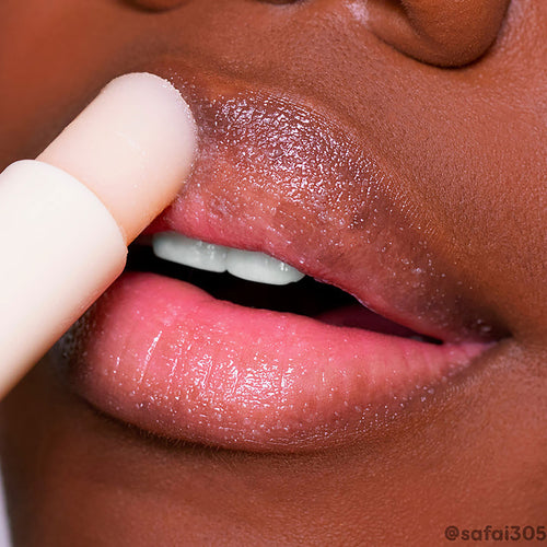 ColourPop Vanilla Lip Scrub stick exfoliating dry lips in a close-up, creamy vanilla balm gliding over the upper lip to buff flakes and reveal a glossy, hydrated finish, with the nude twist-up applicator shown in use.
