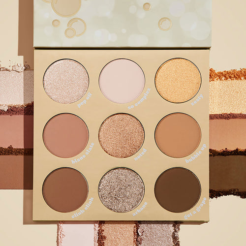ColourPop Feelin' Bubbly shadow palette open, showing a 9-pan range of champagne, gold, taupe, and brown shades in matte and shimmer finishes, set on a cream backdrop with pigment swatches and bubbly-themed beige packaging.