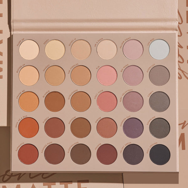 ColourPop Gone Matte Shadow Palette lies open, revealing 30 all-matte eyeshadow pans in 5 rows of 6 - neutral beiges, warm browns, soft pinks, mauves, taupes, and cool grays - set in a beige case on a tan backdrop under soft studio light.
